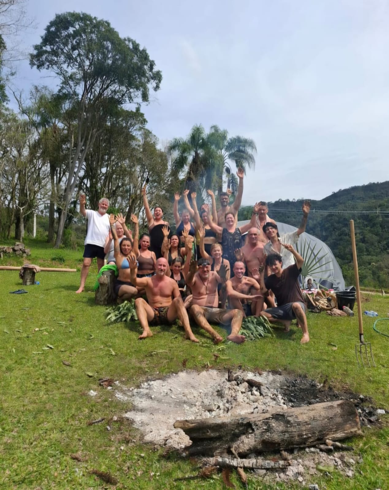 Grupo de participantes com os braços erguidos ao ar livre